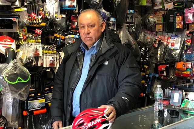 Juan Vicente Valerio stands behind the counter of a bike shop in Jackson Heights. Valerio died of COVID-19 in early April.